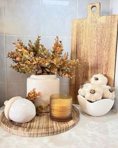 a wooden cutting board sitting on top of a counter next to vases filled with flowers