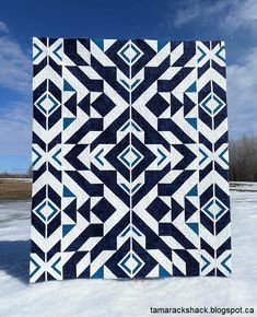 a blue and white quilt on snow covered ground