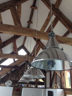 a large metal light hanging from the ceiling in a room with wooden beams and exposed ceilings