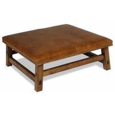 a brown leather ottoman sitting on top of a wooden table