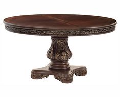 a round wooden table with ornate carvings on the top and base, sitting against a white background