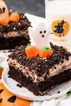 two pieces of cake on a white plate with halloween decorations and candy in the background