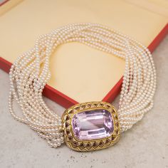 This elegant Mid-Century pearl necklace features a 89.92 carat kunzite and accent diamonds set in 18 karat yellow gold. The kunzite features a lightly saturated lilac hue and is set in a decorative vintage bezel. Twenty-two (22) triangle cut kunzite gems decorate the geometric engraved bezel for added scintillation. One hundred and twenty-six (126) near colorless diamonds are bead set in triangle mountings creating a sparkling accent to the soft purple kunzite. Finished with sixteen strings of p Luxury Pearl Necklace With Gemstones For Formal Occasions, Luxury Akoya Pearl Necklace For Evening, Luxury Kunzite Jewelry For Gifts, Luxury Pearl Pendant Necklace For Evening, Formal Pearl Gemstone Necklace, Elegant Formal Necklace With Gemstone Accents, Formal Pearl Necklace With Gemstone, Formal Akoya Pearl Gemstone Jewelry, Luxury Akoya Pearl Jewelry With Gemstones