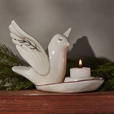 a white dove candle holder with a lit candle