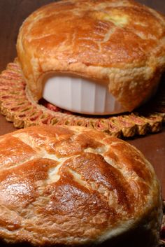 two bread pies sitting on top of a wooden table next to eachother