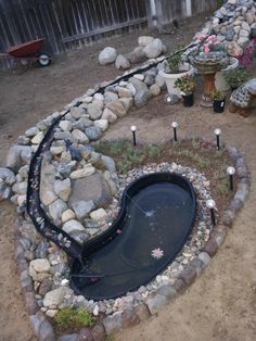 there is a small pond in the middle of this garden with rocks and gravel around it