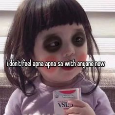 a doll with black makeup holding up a box that says i don't feel apna