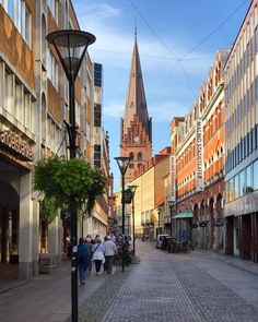 people are walking down the street in an old european city with tall buildings and cobblestone streets