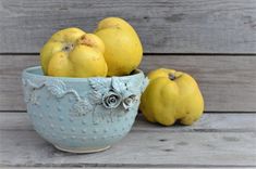 a blue bowl filled with yellow fruit sitting on top of a wooden table