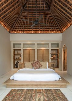 a large bed sitting in the middle of a bedroom next to a ceiling mounted fan