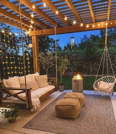 an outdoor living area with swing chairs, rugs and lights on the patio at night