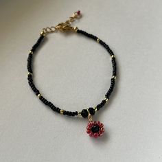 This listing is for one beaded flower charm bracelet with red, black, and gold glass seed beads. These delicate handmade bracelets are made with love and care by an Egyptian-American mother/daughter team. Bracelets measure approximately 6 inches (15.5cm) with 1.5 inch (4cm) extension chain.  Custom sizing and colors available upon request, just send us a message! Materials include: 🌸 Glass seed beads 🌸 Copper gold colored tarnish resistant wire 🌸 Gold plated spacer lobster clap and extension Flower Charm Bracelet, Team Bracelets, Beads Bracelet Design, Black Seed, Seed Bead Bracelets, Gold Glass, Flower Charm, Red Glass, Bracelet Designs