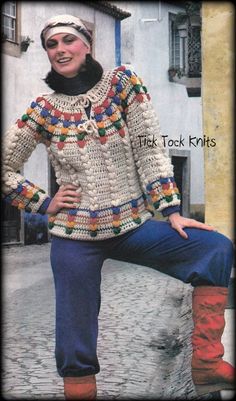 a woman sitting on top of a stone wall next to a building and wearing boots