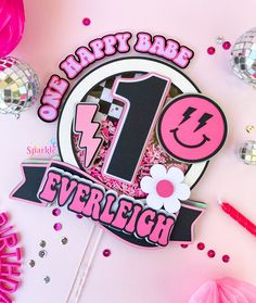 a birthday cake topper with the number one on it and pink decorations around it