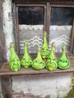 seven green vases with faces painted on them are sitting in front of a window