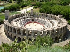 an aerial view of the roman amphit, with trees in the foreground and water in the background