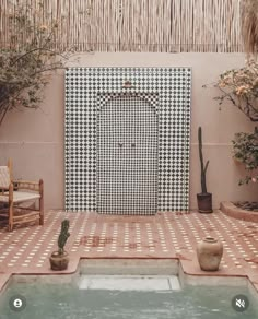 an outdoor pool area with potted plants and a tiled wall in the background, surrounded by greenery