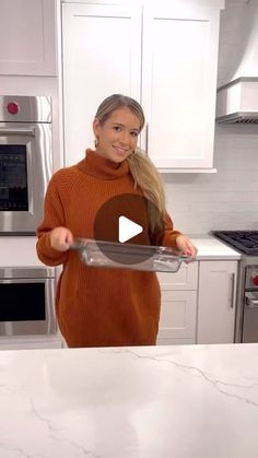 a woman in an orange sweater is holding a pizza pan