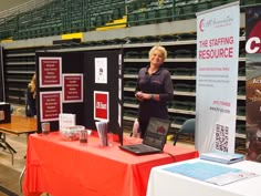 a woman standing next to a table with a laptop on it