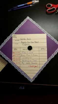 a purple and white graduation cap sitting on top of a table next to some scissors