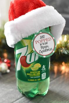 a green bottle with a santa hat on it sitting on top of a wooden table