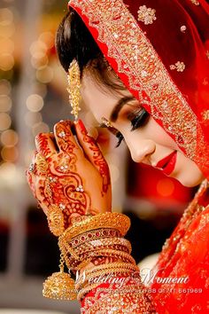 a woman in red and gold holding her hands to her face with henna on