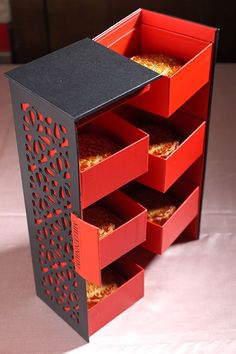 an open red and black box with four trays on it, sitting on a table