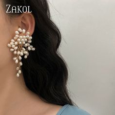 a close up of a person wearing ear clips with pearls on the end of them