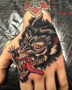 a hand that has a tattoo on it with a wolf's head and red eyes