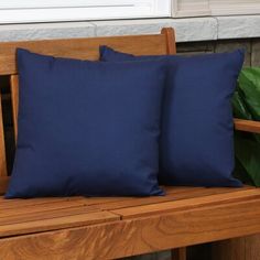 two blue pillows sitting on top of a wooden bench