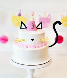 a white cake with pink frosting and a cat hat on it's top