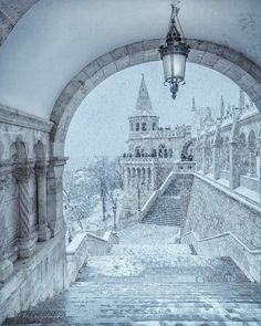 an arch with stairs leading to a building and a street light hanging from it's side