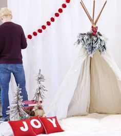 a man standing next to a teepee with christmas decorations on it