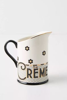 a ceramic pitcher with the word creme painted on it's side and black handles