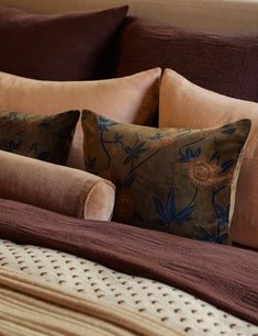 a bed with brown and blue pillows on top of it's headboard in a bedroom