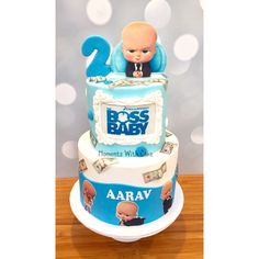 a blue and white cake with a baby on top that says boss baby, it's his first birthday