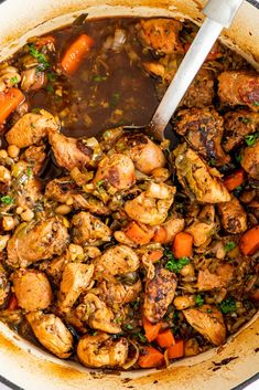 a pot filled with chicken and vegetables next to a spoon