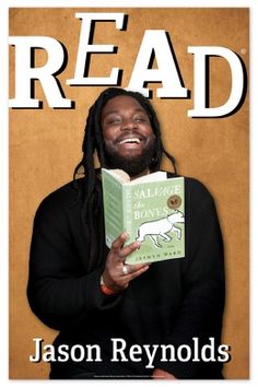 a man with dreadlocks holding a book in front of his face and smiling