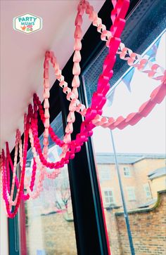 pink and red streamers are hanging from the ceiling in front of a large window