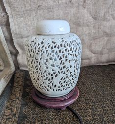 a white vase sitting on top of a wooden stand