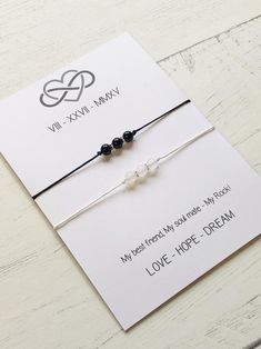 two black and white bracelets on top of a card with the words love, hope, dream