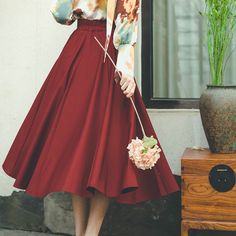 a woman in a red skirt holding a flower