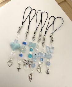 a bunch of necklaces that are laying on a white surface with some charms attached to them