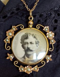 This finely crafted window style portrait pendant has convex glass on both sides so that two images may be shown.  At present there is an old sepia photo of a gentleman on one side. * Tiny seed pearls decorate a scroll work and floral surround. *  Locket is opened by unscrewing the knob at the top. * Comes with the original 40.5cm trace link chain. *  Stamped 9ct to the reverse. *  Gold has a two tone effect with the use of yellow and rose gold. Dimensions:  Inside glass 24mm diameter.  Top of fixed ring to bottom of pendant:  40mm. In very good antique condition.  Please see photos for more detail. Antique Portraits, Scroll Work, A Gentleman, Window Styles, Pendant With Chain, Seed Pearl, Link Chain, Gold Pendant, Locket