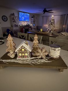 three gingerbread houses are sitting on a table with candles in the shape of christmas trees