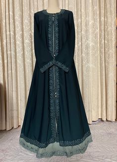 Elegant beautiful embroidery and stonework dark teal green (bottle green) abaya with a contrast color front double bottom embroidered finish.  Soft, lightweight flowy fabric suitable for all weather conditions, best pick for hot summer temperatures.  Front closed burqa with decorative shiny stone buttons in super high premium quality fabric. Available in size 52. (This abaya does not come with a matching scarf.) Green Abaya, Stone Buttons, Dark Teal Green, Summer Temperature, Head Coverings, Flowy Fabric, Hijab Scarf, Green Bottle, Under Dress