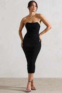 a woman in a black dress posing for the camera with her hands on her hips