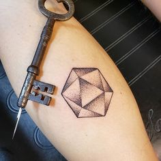 a person with a tattoo on their arm holding a key to a diamond shaped object