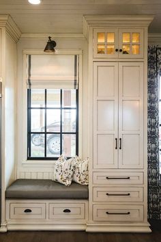 a window seat in the corner of a room next to a refrigerator and cupboards