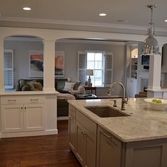 a kitchen with an island, sink and living room in the backgrounge